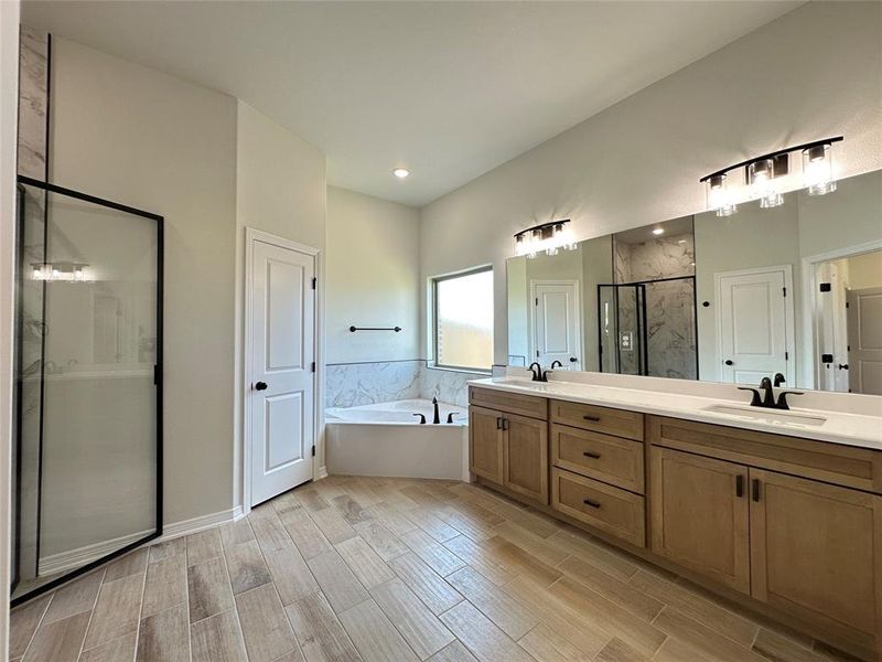 Full bath with a marble finish shower, double vanity, a garden tub, and wood tiled floors