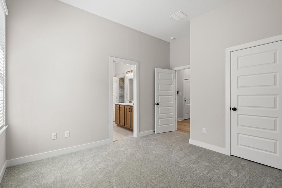 Unfurnished bedroom featuring light colored carpet and ensuite bath