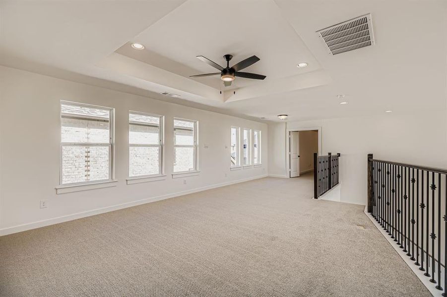 Empty room featuring a raised ceiling, light carpet, recessed lighting, and ceiling fan Empty room featuring a raised ceiling, light carpet, recessed lighting, and ceiling fan