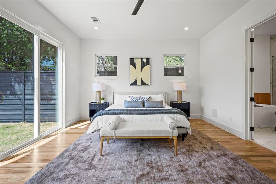 Bedroom with multiple windows, ensuite bath, and light hardwood / wood-style flooring