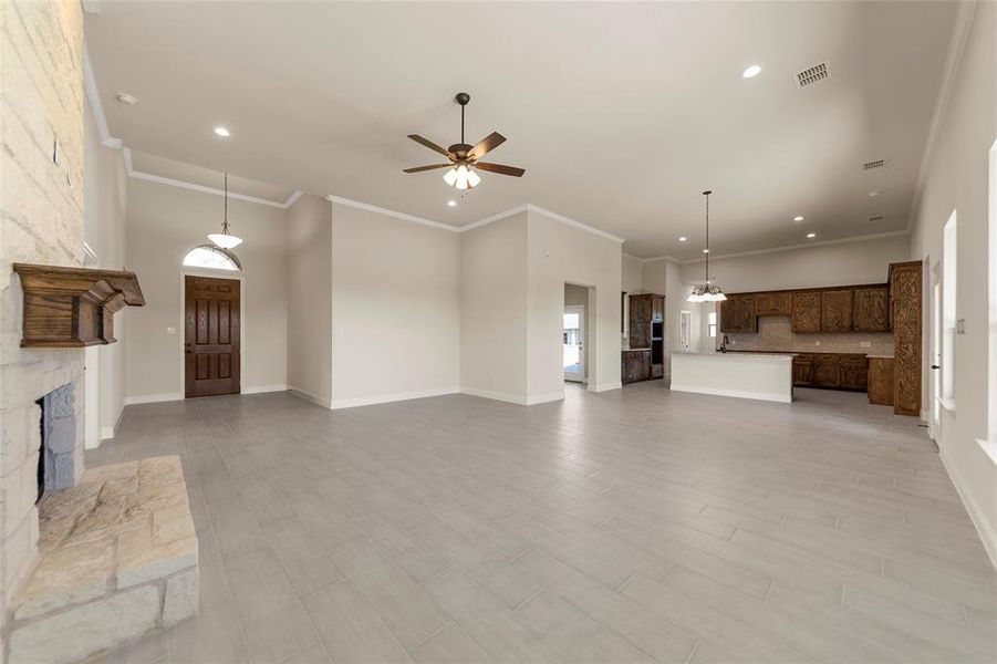 Unfurnished living room with ceiling fan, sink, crown molding, light hardwood / wood-style floors, and a fireplace