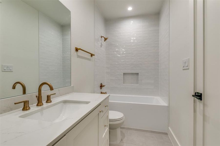 Full bathroom with vanity, tiled shower / bath combo, toilet, and tile patterned floors