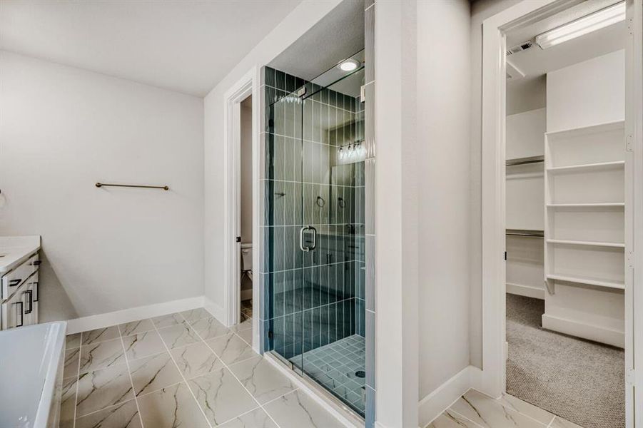 Bathroom with vanity, light marble finish flooring, a shower stall, and a walk in closet
