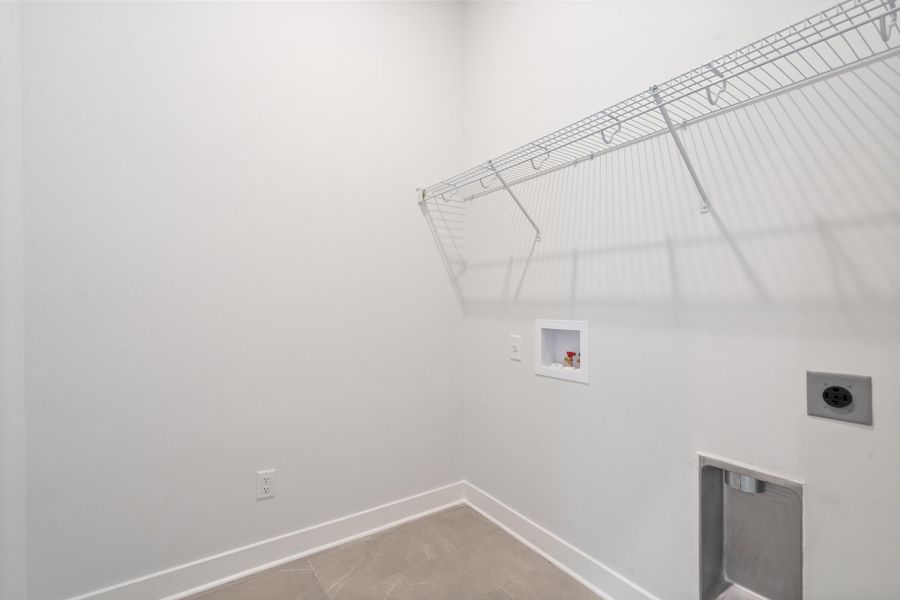 Utility space featuring tile flooring, wire shelving, and appliance hookups
