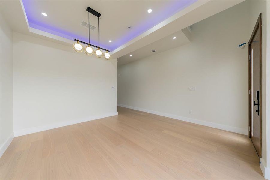 Living Room featuring a raised ceiling, recessed lighting, and light wood finished floors