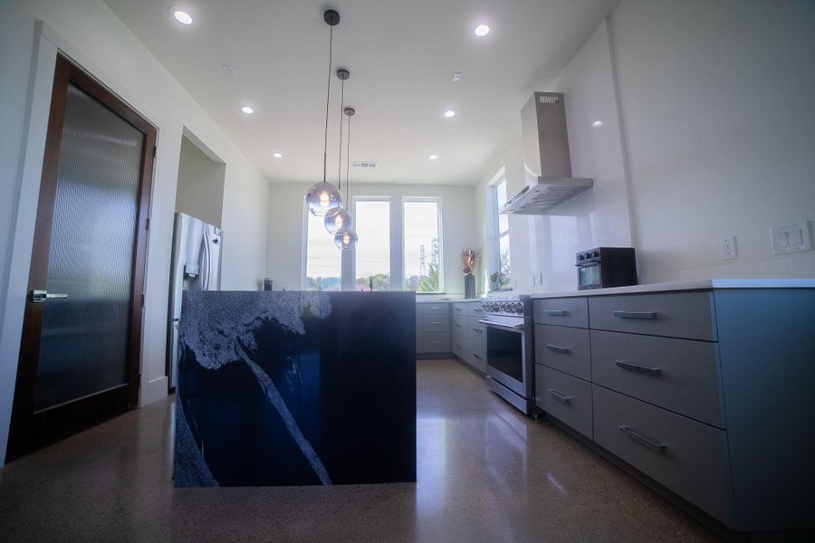 The gourmet  kitchen is anchored by a massive center island featuring a waterfall countertop, creating a seamless and sophisticated architectural statement that is as durable as it is beautiful.