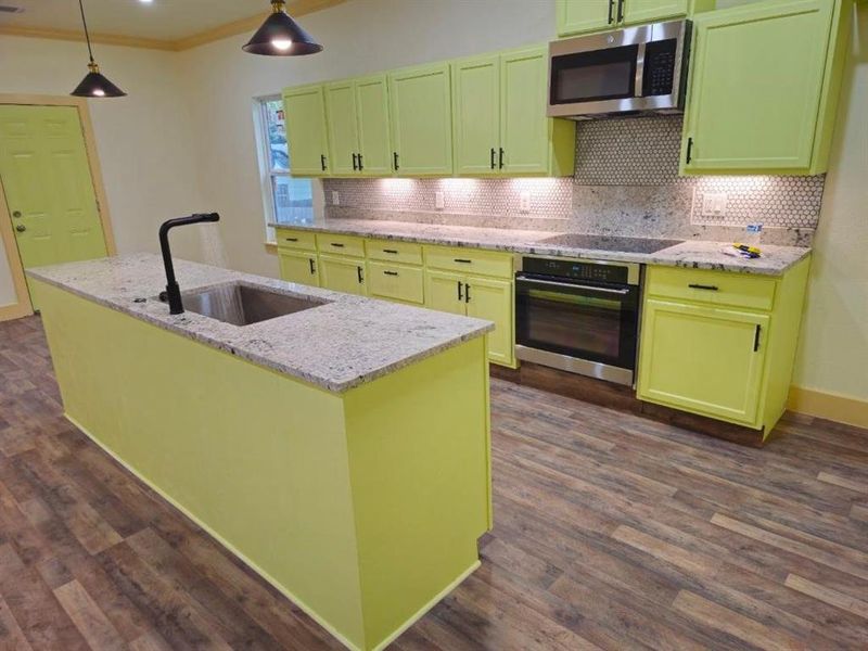 Kitchen with sink, ornamental molding, an island with sink, appliances with stainless steel finishes, and light stone counters