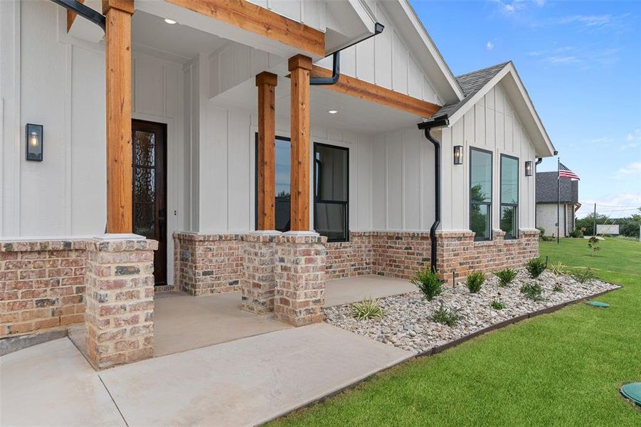 Entrance to property with covered porch and a yard