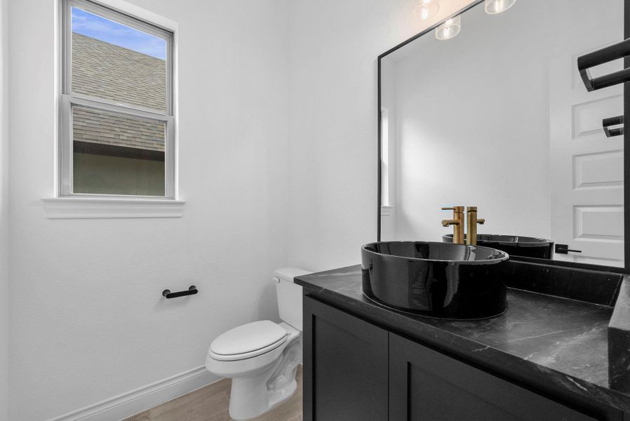 Modern powder bath with sleek black vanity, vessel sink, and contemporary fixtures.