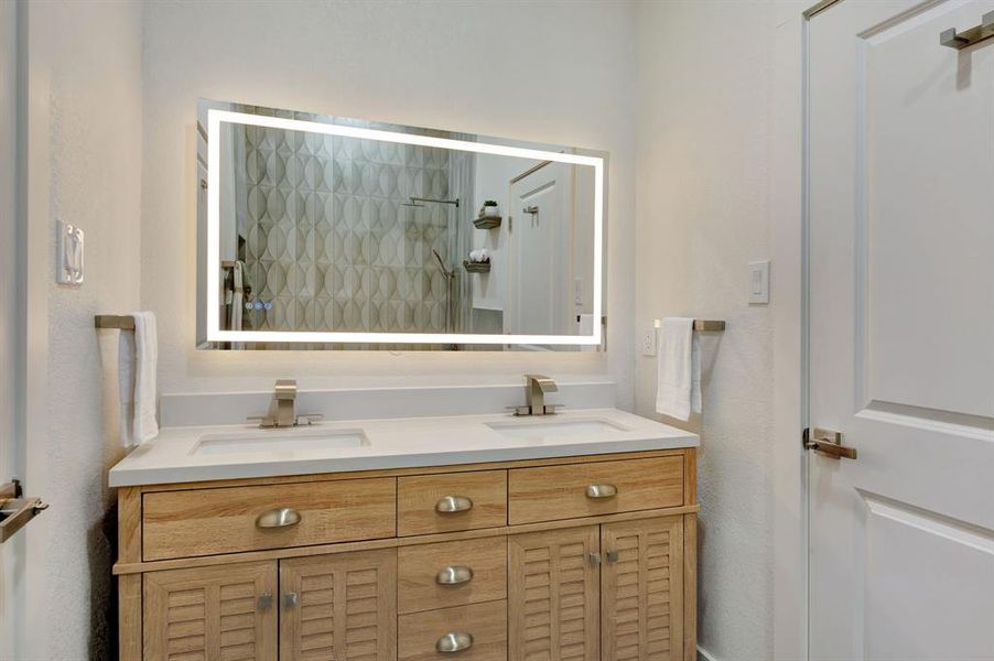 Dual vanity featuring a light wood-finish cabinet with louvered doors and drawers, under-mount sinks, and brushed nickel hardware Dual vanity featuring a light wood-finish cabinet with louvered doors and drawers, under-mount sinks, and brushed nickel hardware