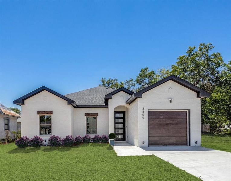 View of front of property featuring a front lawn and a garage