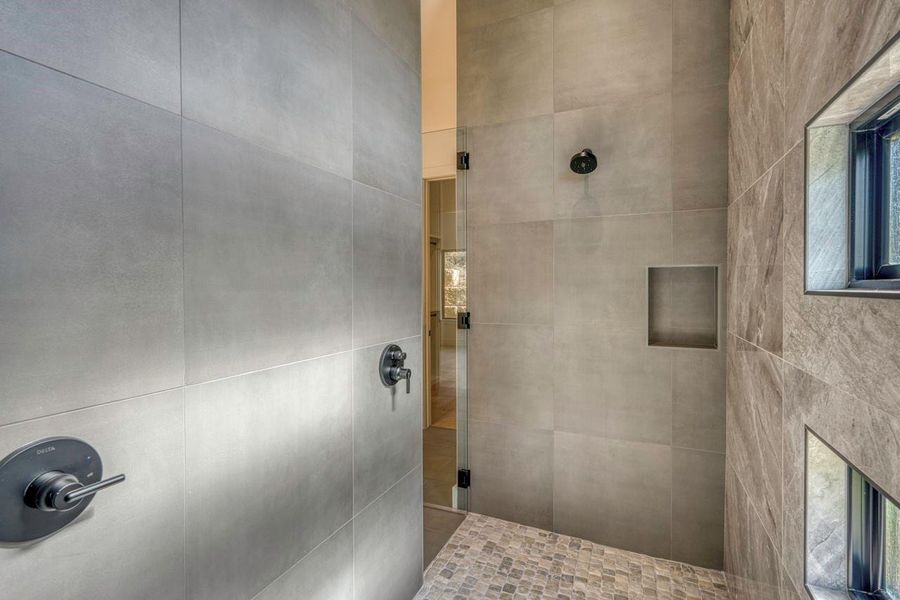 Textured tile walls and mosaic stone flooring define this modern walk-in shower design. Textured tile walls and mosaic stone flooring define this modern walk-in shower design.