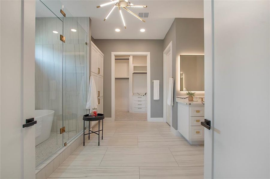 Bathroom featuring tile floors, an inviting chandelier, a shower with shower door, and vanity