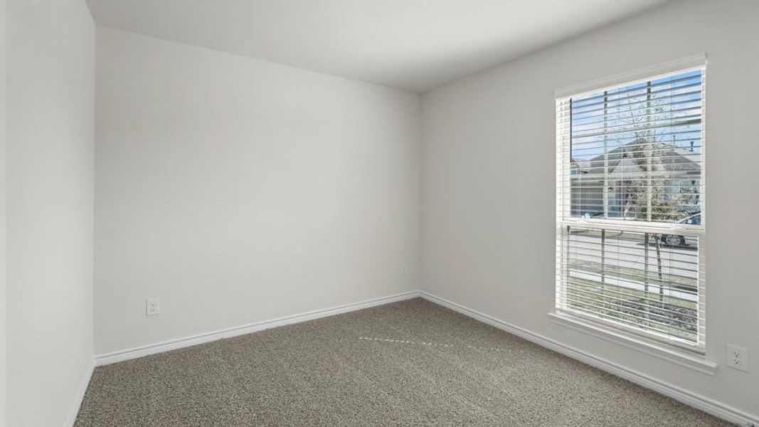 This room features neutral-toned walls, gray carpeting, and a window with blinds, allowing for natural light