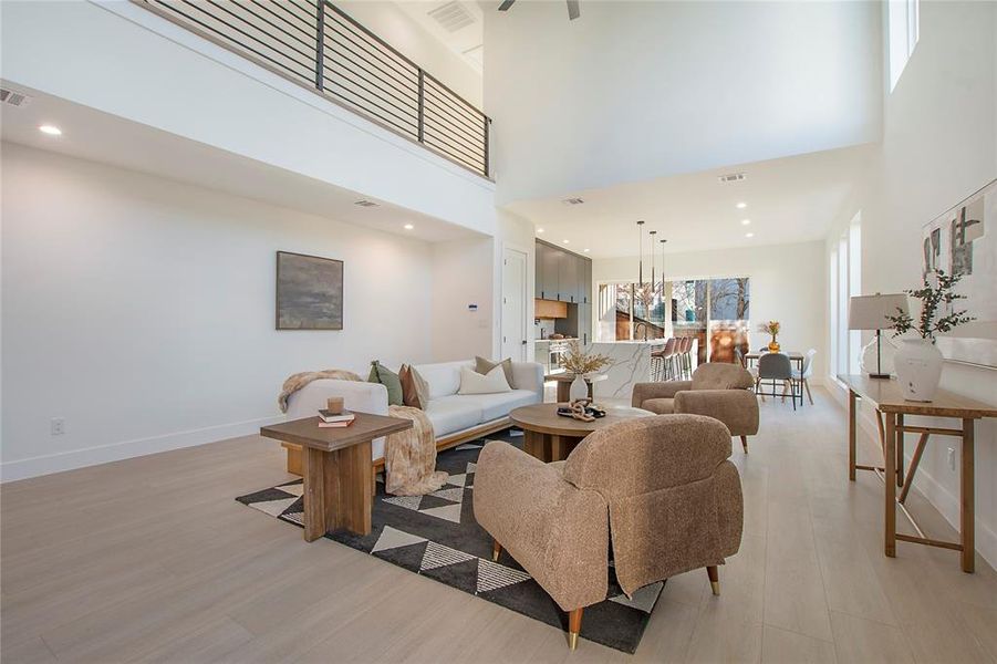 Living room with a high ceiling and light wood-type flooring