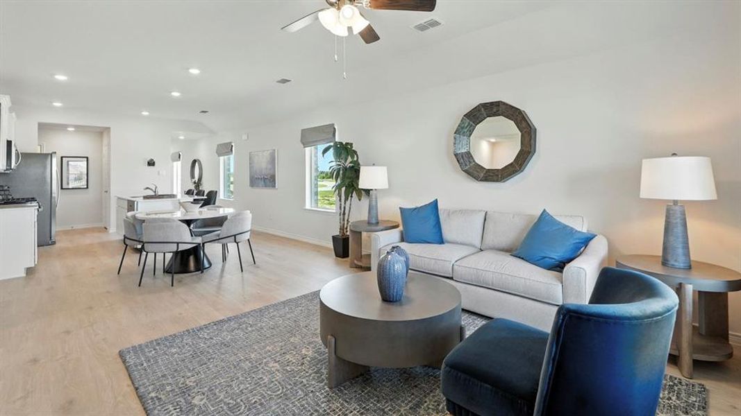 Living area featuring light wood-style floors, ceiling fan, recessed lighting, and vaulted ceiling
