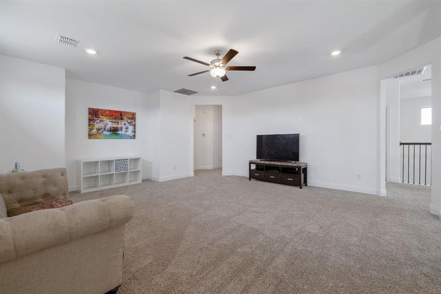 Carpeted living area featuring baseboards, ceiling fan, visible vents, and recessed lighting