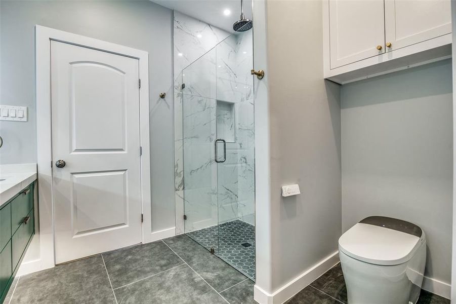 Bathroom featuring tile patterned flooring, vanity, a shower with door, and toilet