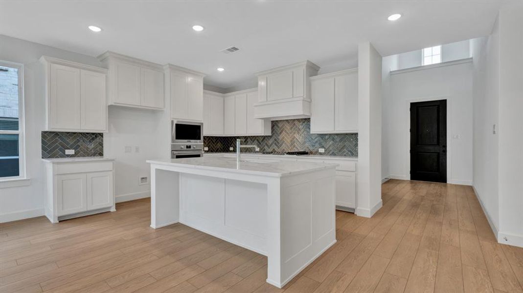 Kitchen featuring stainless steel appliances, backsplash, and light hardwood / wood-style flooring