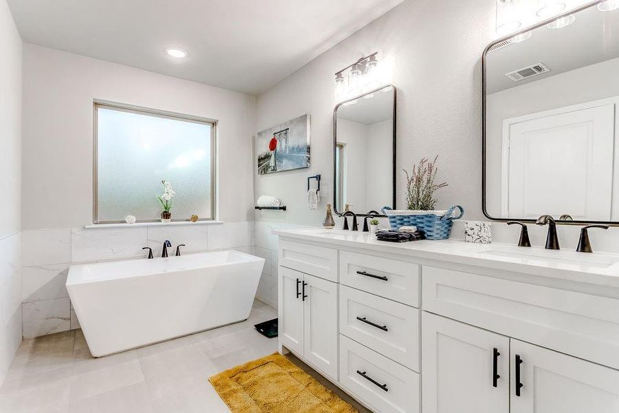 Bathroom with tile patterned floors, a washtub, vanity, and tile walls