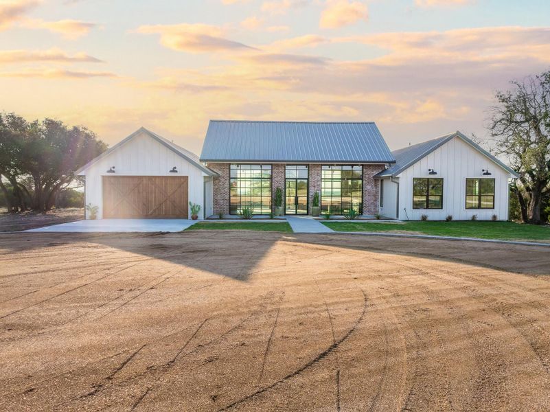 Modern farmhouse style home featuring board and batten siding, a garage, concrete driveway, and a metal roof