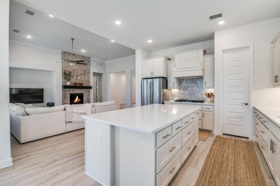 Kitchen featuring a ceiling fan, gas cooktop, high quality fridge, premium range hood, and visible vents Kitchen featuring a ceiling fan, gas cooktop, high quality fridge, premium range hood, and visible vents