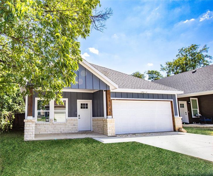 Ranch-style house with roof with shingles, board and batten siding, a front yard, driveway, and a garage