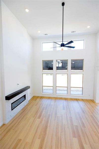 Unfurnished living room with healthy amount of natural light, light wood-style flooring, a fireplace, a ceiling fan, and recessed lighting Unfurnished living room with healthy amount of natural light, light wood-style flooring, a fireplace, a ceiling fan, and recessed lighting