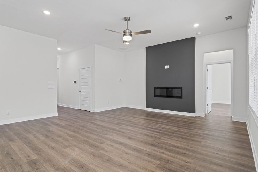 Unfurnished living room with a ceiling fan, a large fireplace, recessed lighting, and wood finished floors