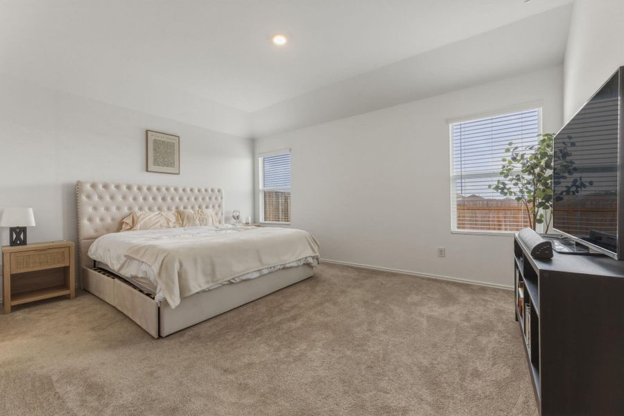 This bedroom features carpeted flooring, white walls, and two windows with blinds