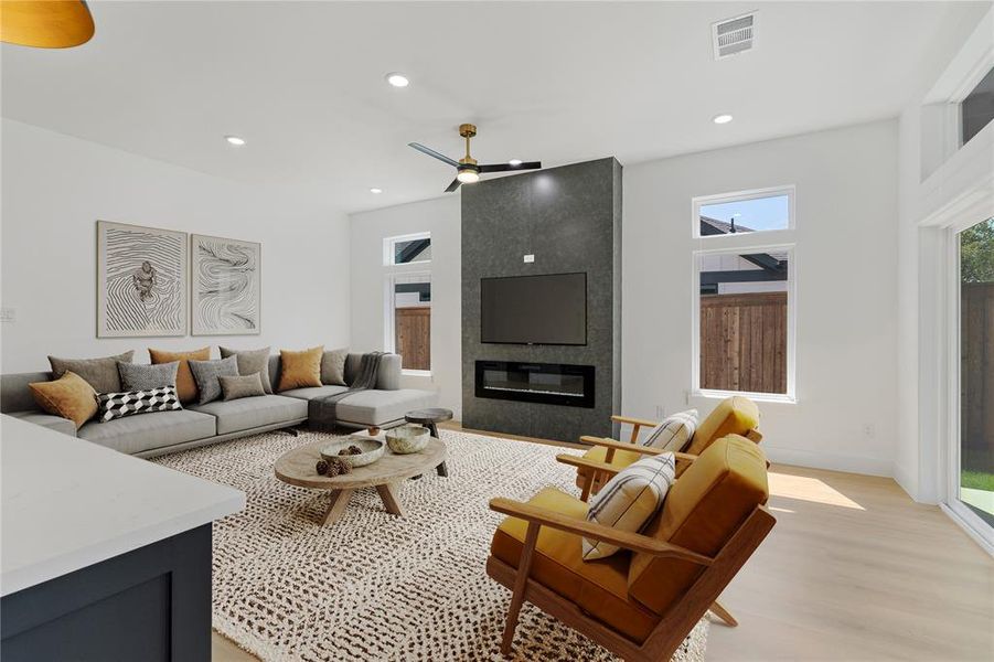 Living room featuring a fireplace, ceiling fan, plenty of natural light, and light hardwood / wood-style floors