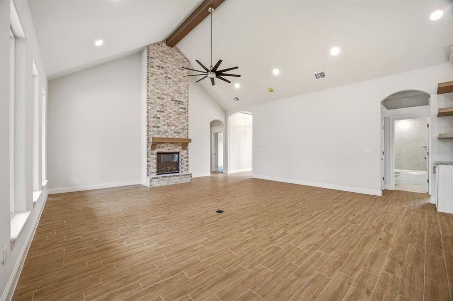 Unfurnished living room with arched walkways, wood tiled floors, a brick fireplace, a ceiling fan, and recessed lighting Unfurnished living room with arched walkways, wood tiled floors, a brick fireplace, a ceiling fan, and recessed lighting