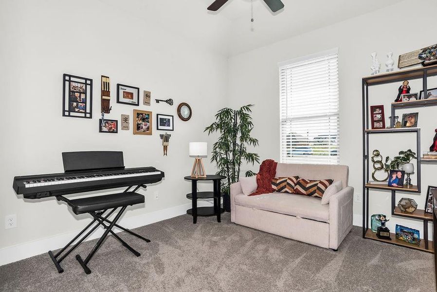 Bright interior room with ceiling fan, carpeted flooring, and light-colored walls