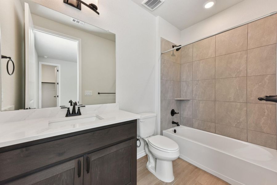 Full bath featuring  shower combination, vanity, light wood-style flooring, and recessed lighting