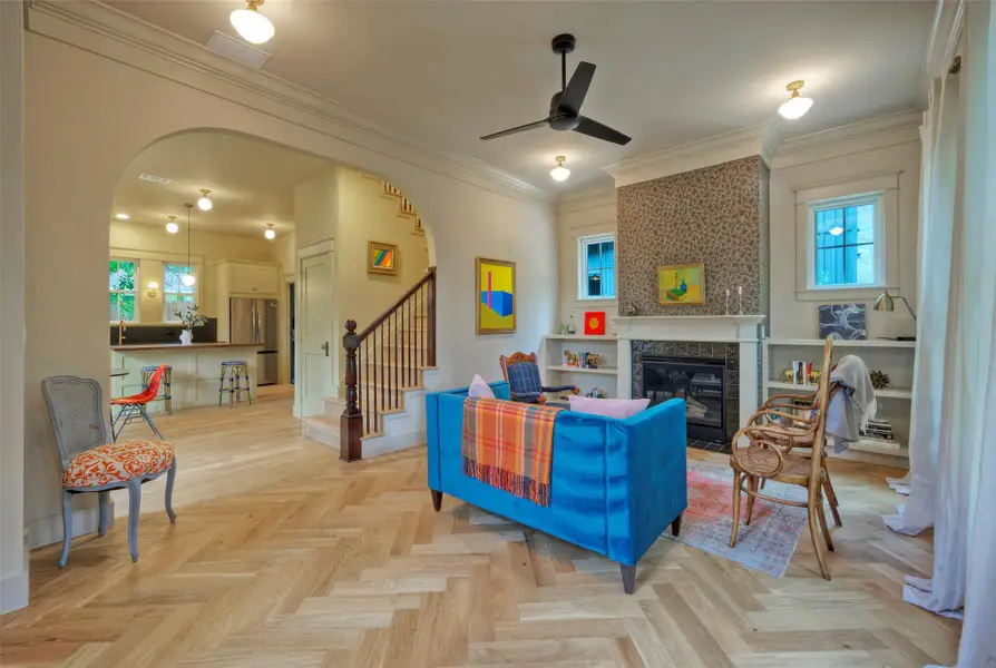 Herringbone hardwood floors extend through an open-concept living space, featuring an inviting fireplace and integrated shelving.