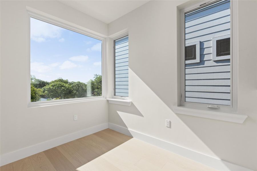 Crisp white walls and clean-lined windows frame leafy neighborhood views in this sun-drenched space.