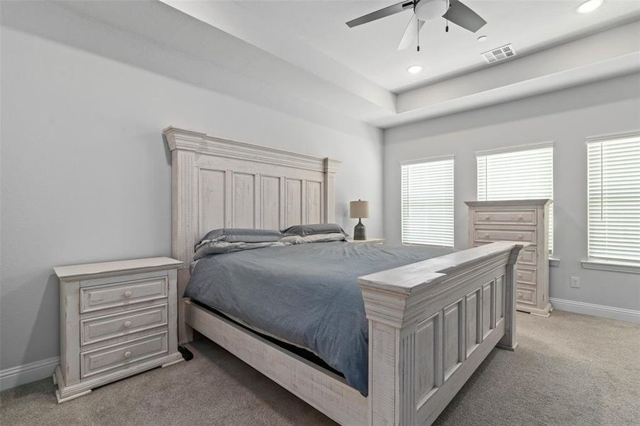 Bedroom with ceiling fan, light colored carpet, and multiple windows