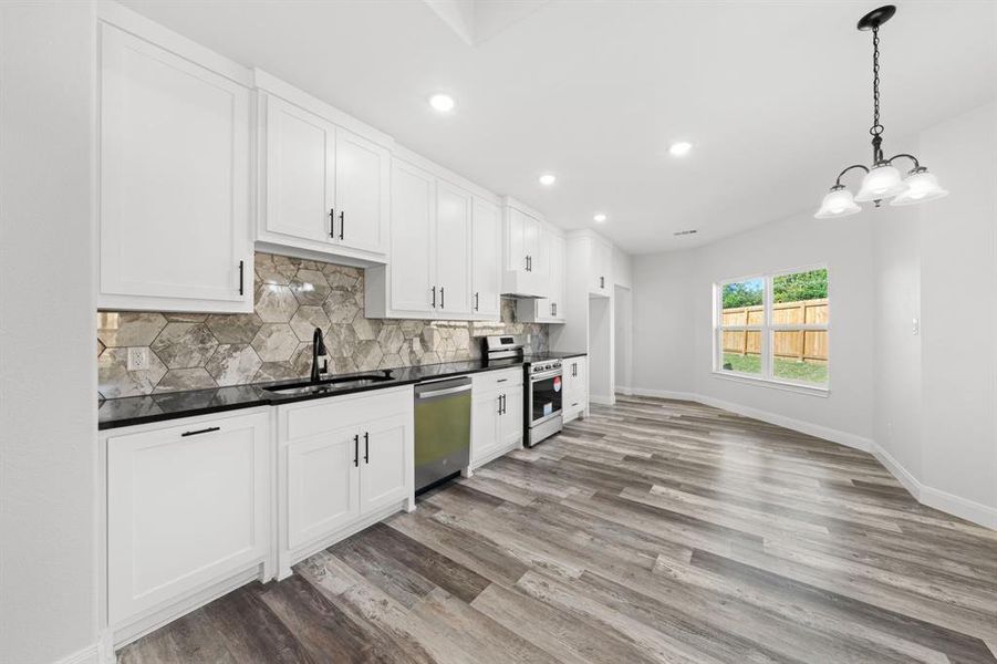 Kitchen with decorative backsplash, dark countertops, stainless steel appliances, light wood-style floors, and recessed lighting Kitchen with decorative backsplash, dark countertops, stainless steel appliances, light wood-style floors, and recessed lighting