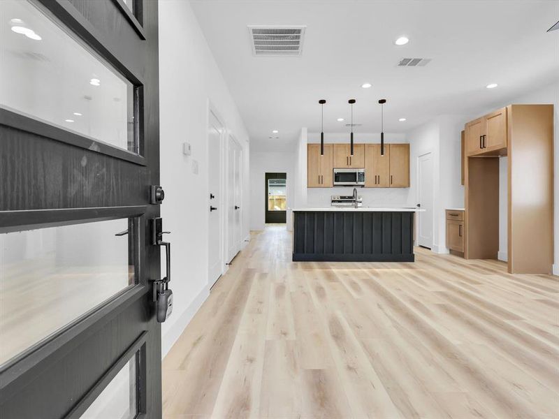 Kitchen featuring decorative light fixtures, a kitchen island with sink, and light wood-type flooring