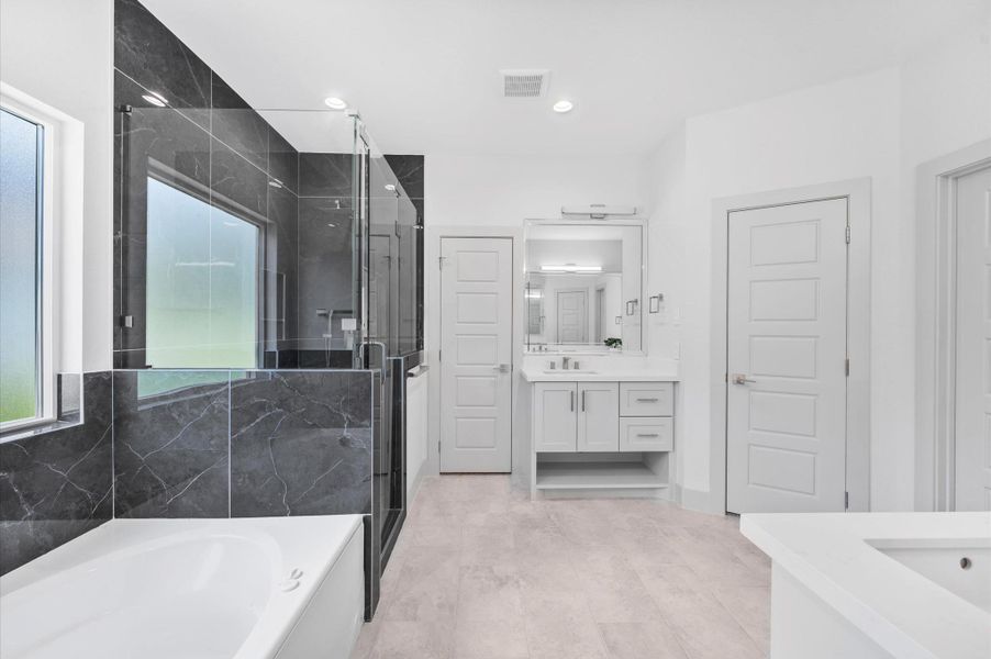 This modern bathroom features a spacious layout with a glass-enclosed shower, a large bathtub, sleek black marble accents, and a dual-sink vanity with ample storage. The bright lighting and neutral color palette add a touch of elegance. This modern bathroom features a spacious layout with a glass-enclosed shower, a large bathtub, sleek black marble accents, and a dual-sink vanity with ample storage. The bright lighting and neutral color palette add a touch of elegance.