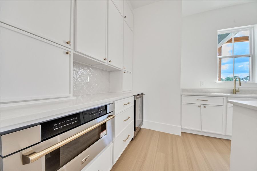 Butler’s pantry featuring custom cabinetry, built-in microwave, mini refrigerator, sink, and abundant storage. Butler’s pantry featuring custom cabinetry, built-in microwave, mini refrigerator, sink, and abundant storage.