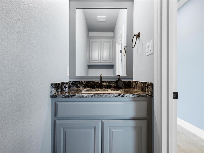 Bathroom featuring vanity, light wood-style floors, and a textured wall Bathroom featuring vanity, light wood-style floors, and a textured wall