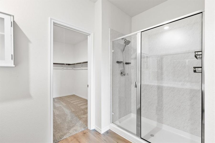Glass-enclosed shower with a rainfall showerhead and integrated shelving