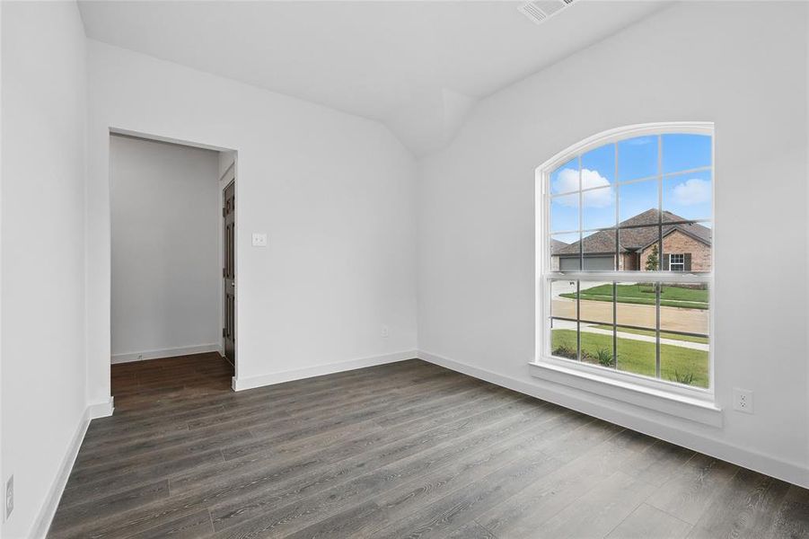 Unfurnished room with vaulted ceiling and dark wood-style floors Unfurnished room with vaulted ceiling and dark wood-style floors