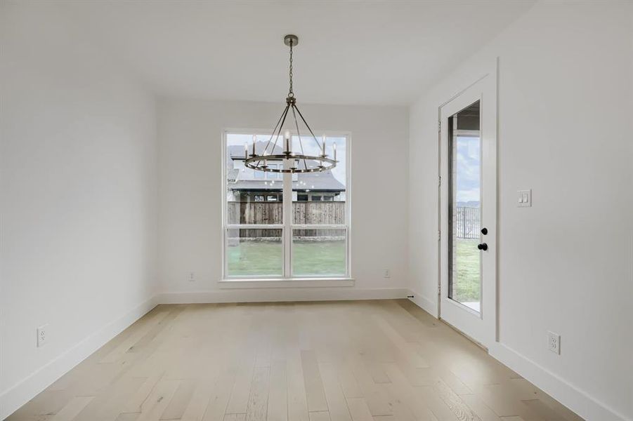 Unfurnished dining area with suspended lighting and light wood finished floors