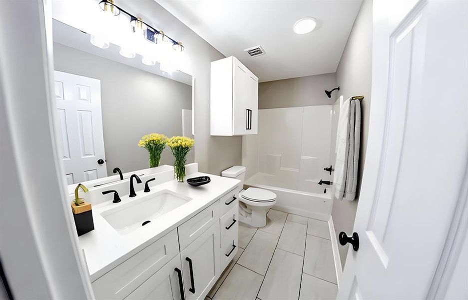 Full bathroom featuring vanity, bathing tub / shower combination, and light tile patterned floors Full bathroom featuring vanity, bathing tub / shower combination, and light tile patterned floors