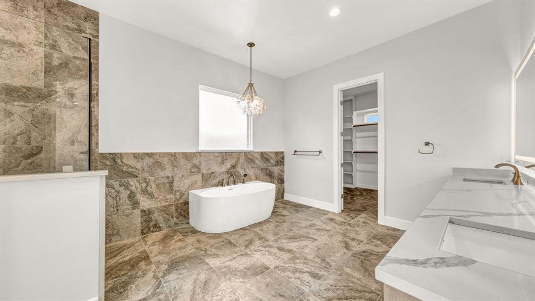 Bathroom with vanity, a bathing tub, and a notable chandelier