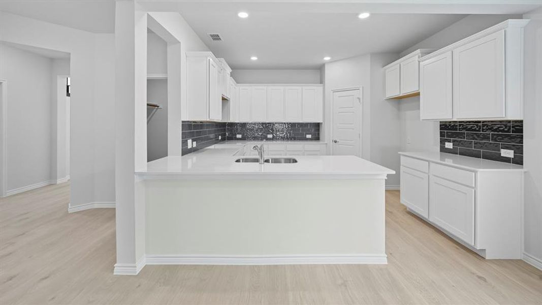 Kitchen with white cabinetry, light stone counters, decorative backsplash, a peninsula, and recessed lighting Kitchen with white cabinetry, light stone counters, decorative backsplash, a peninsula, and recessed lighting
