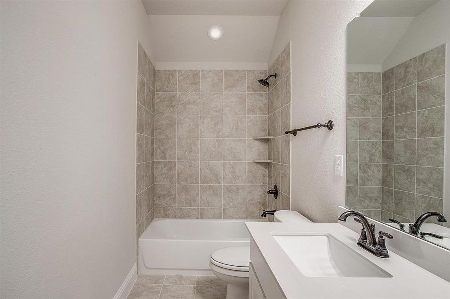 Full bathroom with vanity, tile patterned flooring, tiled shower / bath, and toilet