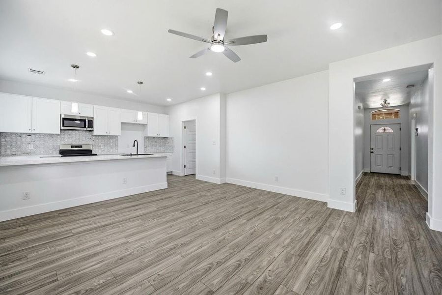 Open-concept living space featuring wood-finish flooring, recessed lighting, and a ceiling fan Open-concept living space featuring wood-finish flooring, recessed lighting, and a ceiling fan